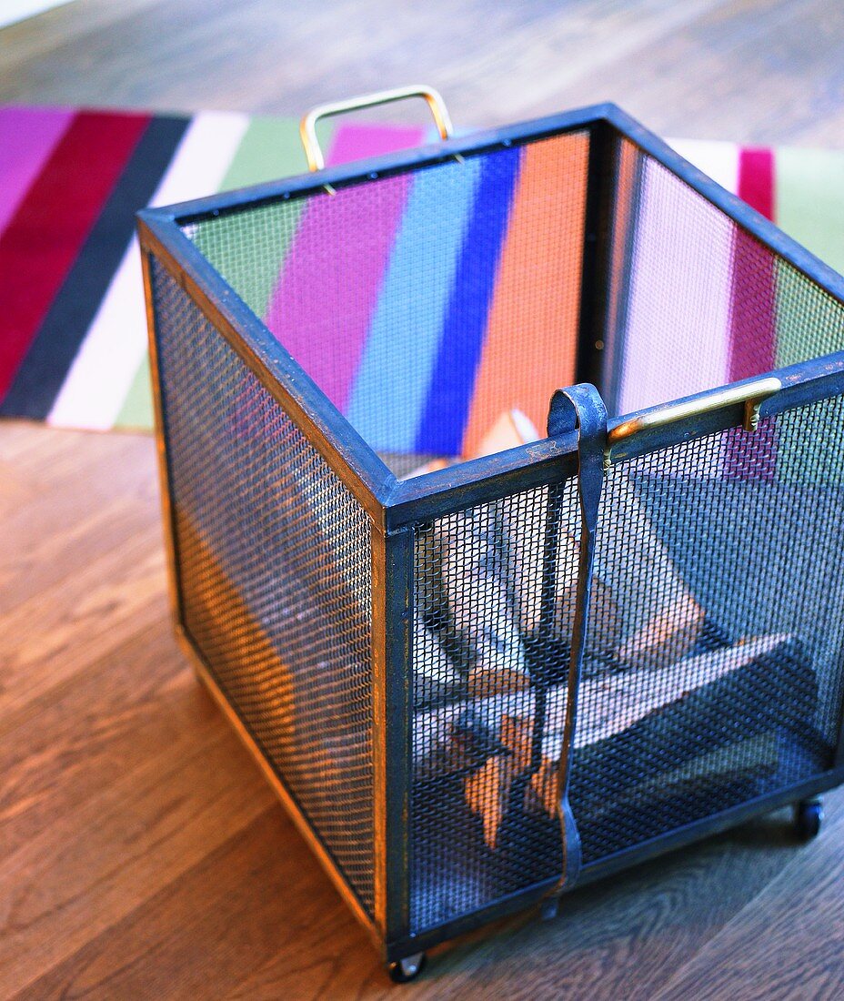 Metal basket out of mesh with wooden logs