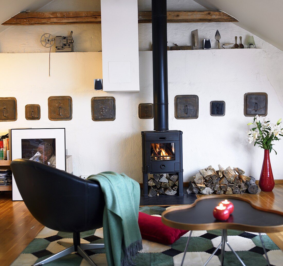 Living room under a ceiling with lounge chair and side table in front of a wood burning stove