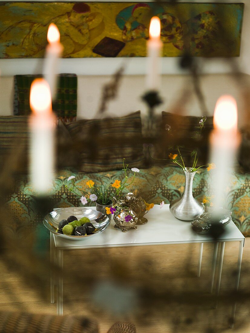 Blick durch gehängtem Kerzenleuchter auf Metalltisch mit Blumenvasen