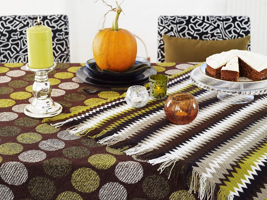 Candle light, pumpkin and cake on a tablecloth with many different designs