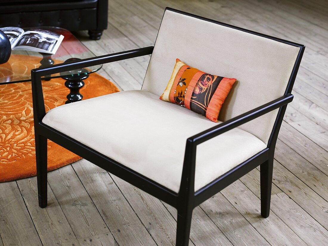 Upholstered armchair with black wooden frame on a rustic wood plank floor