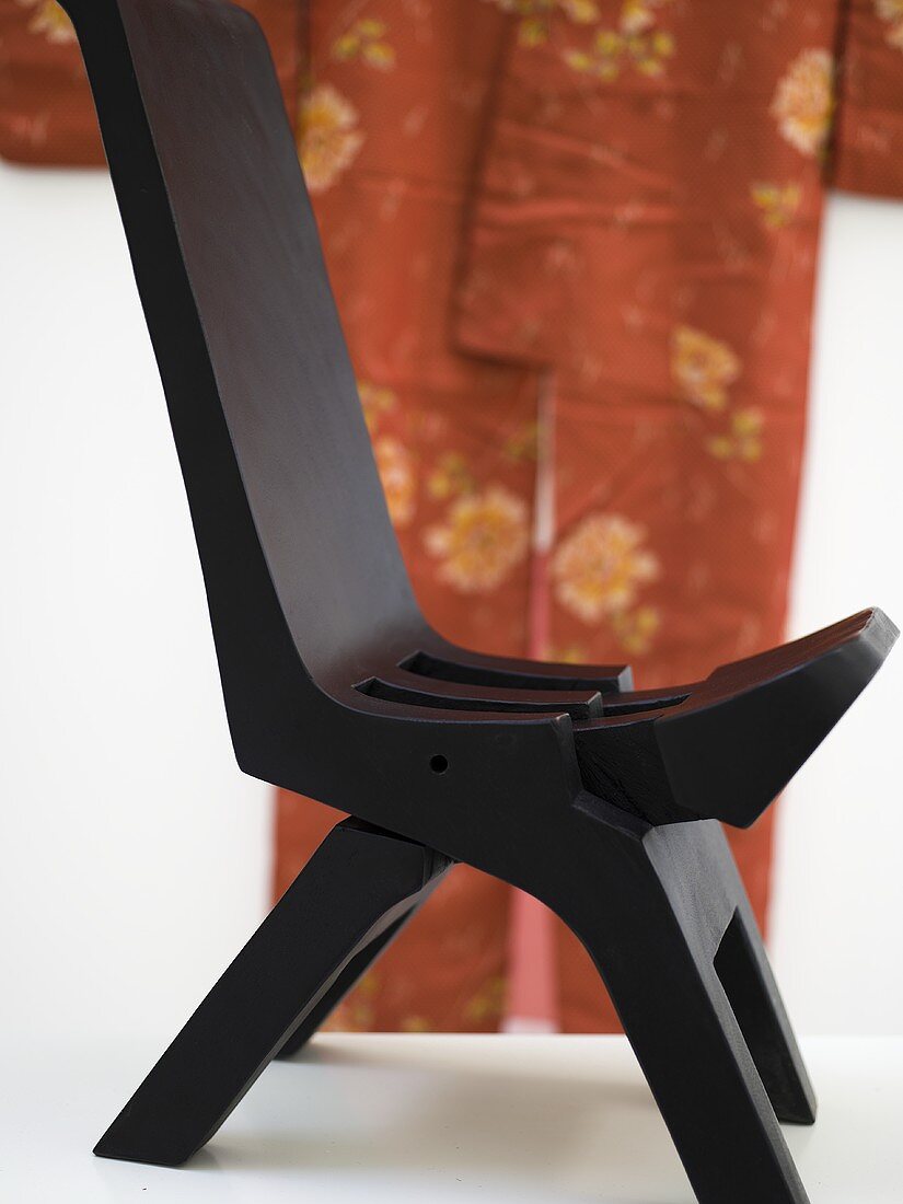 Schwarzer Stuhl im Kolonialstil vor orangenem Kimono