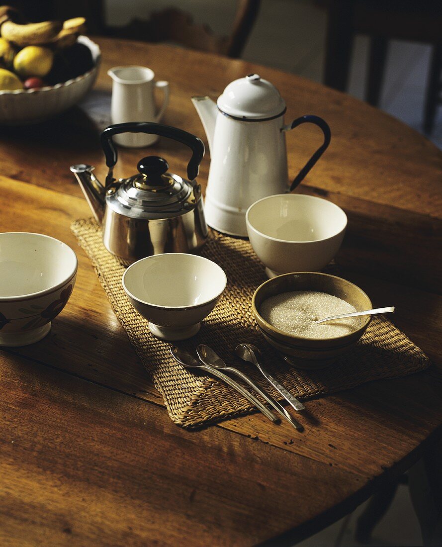 Ceramic bowls, a kettle and an enamel jug on a wooden table