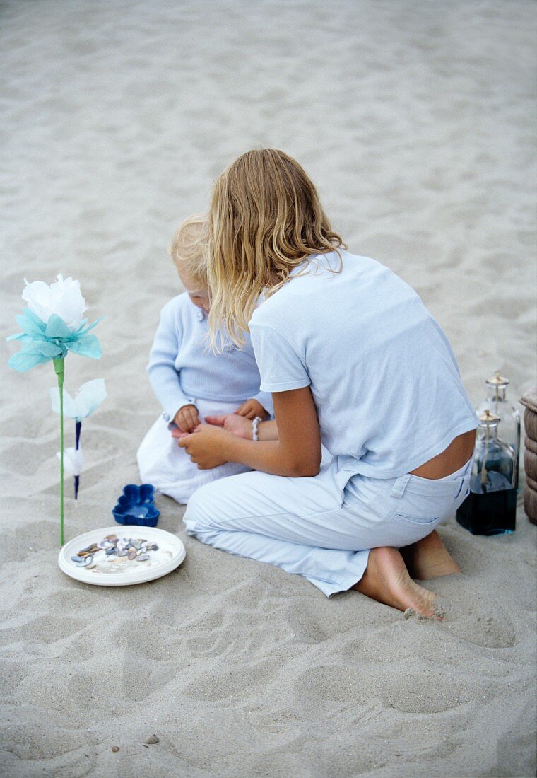 A girl playing on a beach with a small child