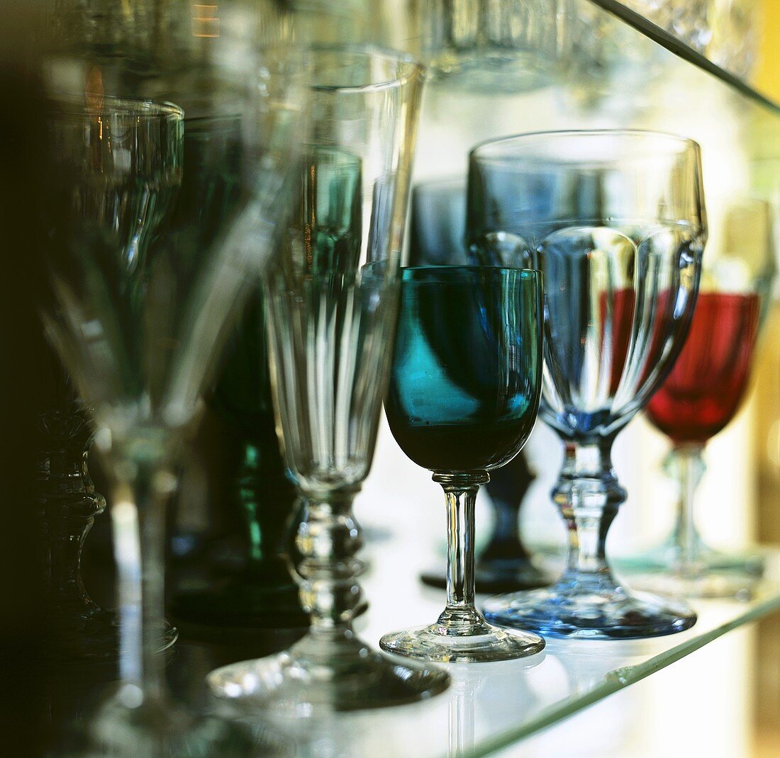 Various glasses on a glass shelf