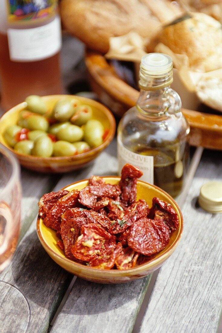 Dried tomatoes, olives and olive oil on a garden table