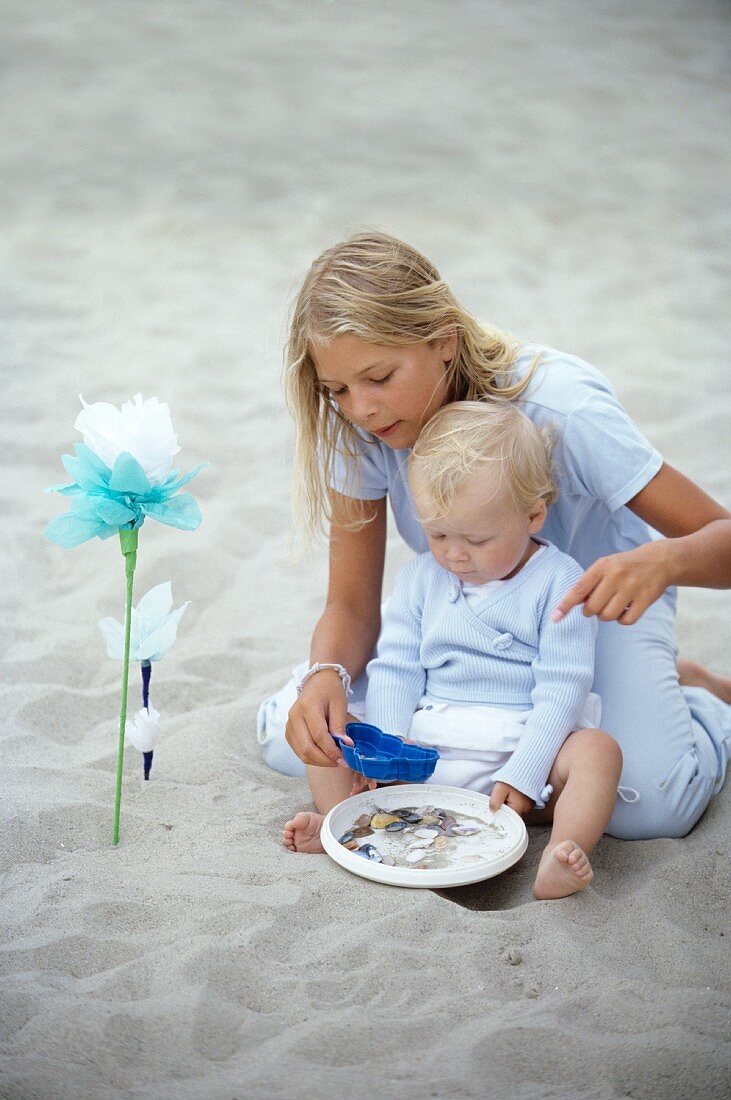 Mädchen spielt mit kleinem Kind im Sand