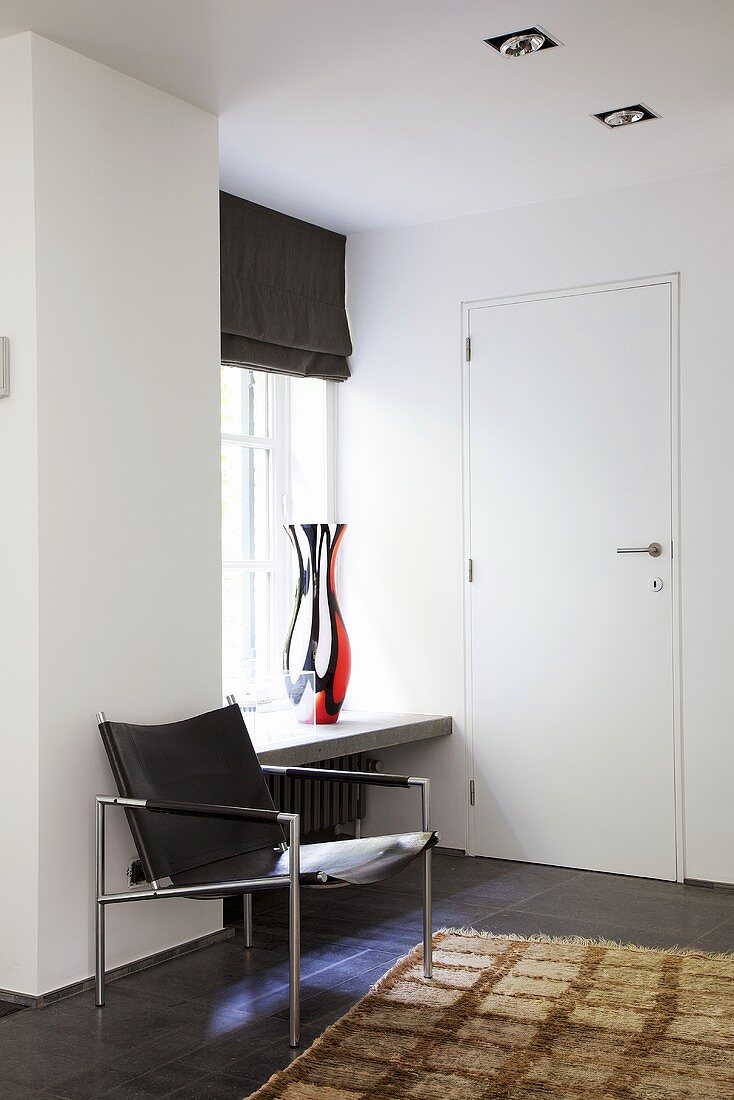 A black leather chair in the entrance way on black floor tiles