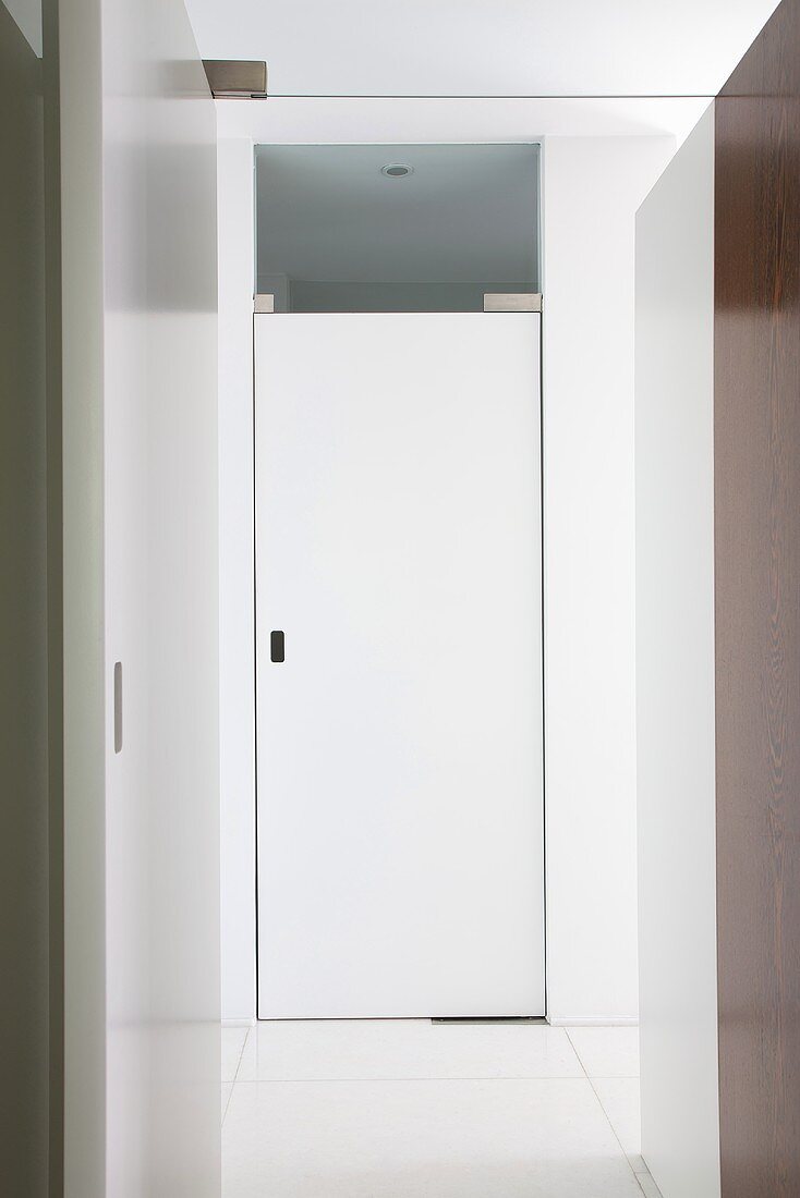 A white apartment door with built-in units and a door to a room at the end of the hallway