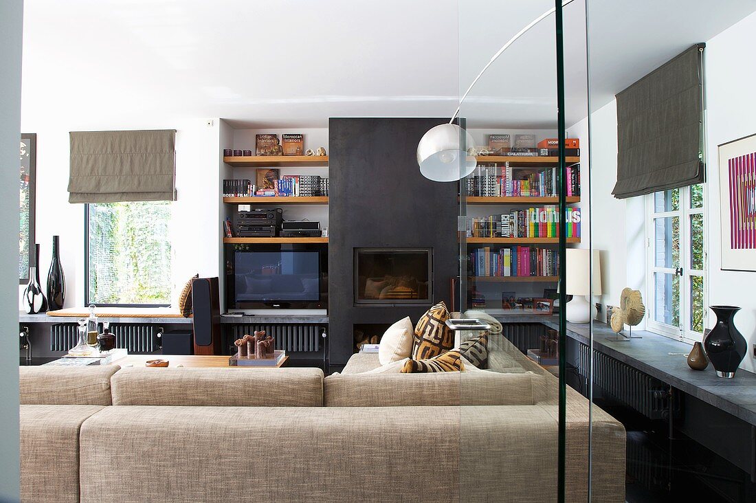 A living room with a black, built-in fireplace between built-in shelves with a hanging floor lamp