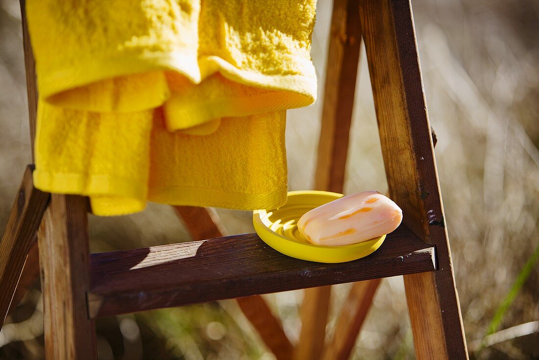 Seife in gelber Schale und Handtuch auf Holzleiter