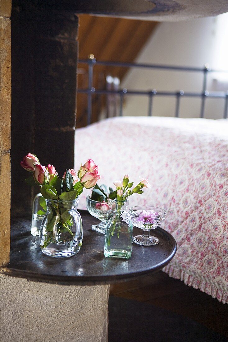 Rosen und Nelken in Glasvase auf Ablage im Schlafzimmer