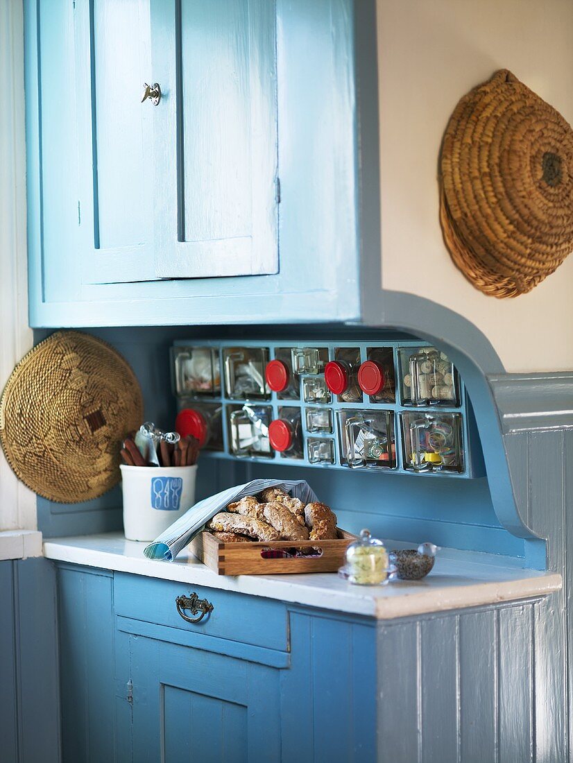 A kitchen counter with a blue wooden front and integrated preserving jars