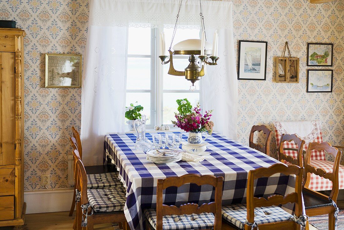 Gemütliche Bauernstube - Esstisch mit karierter Tischdecke vor Fenster