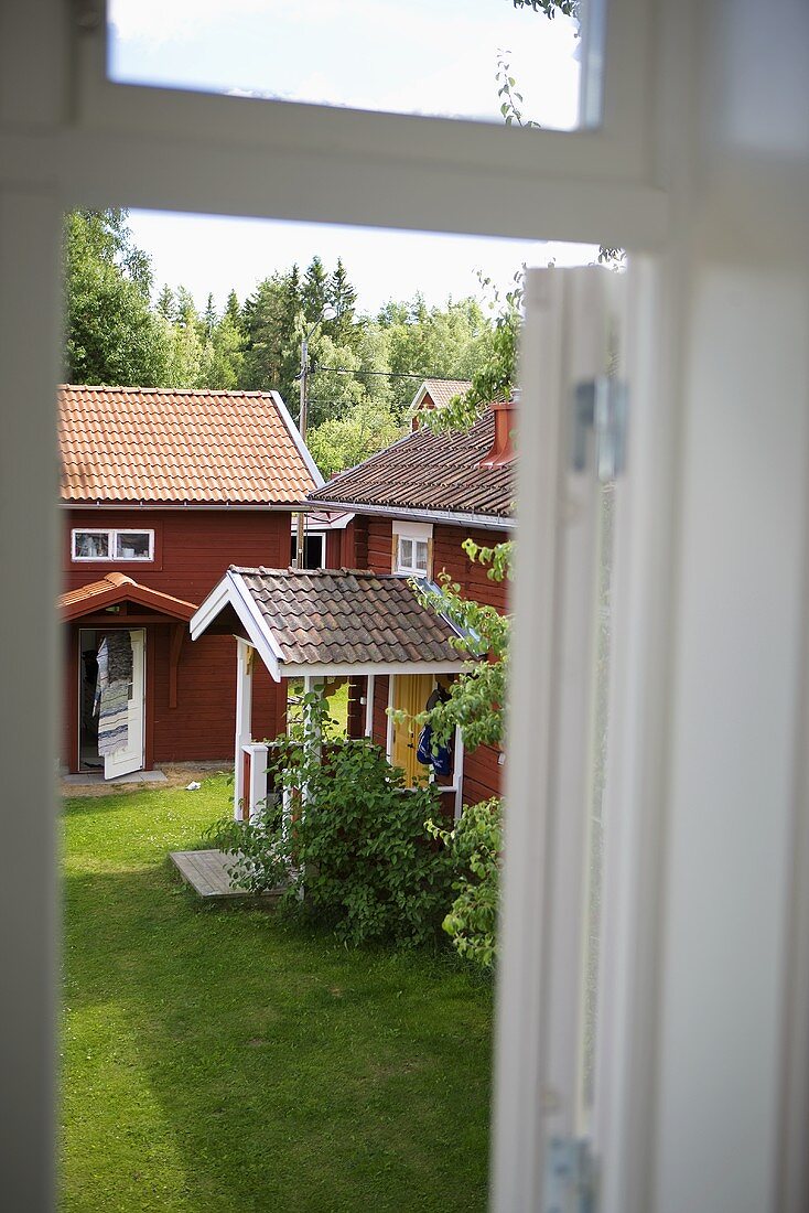 Blick durch Fenster auf Holzhaus mit überdachten Hauseingang