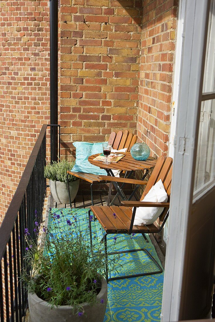 Sonniges Plätzchen auf Balkon vor Ziegelfassade mit Holzstühle und Lavendeltöpfen