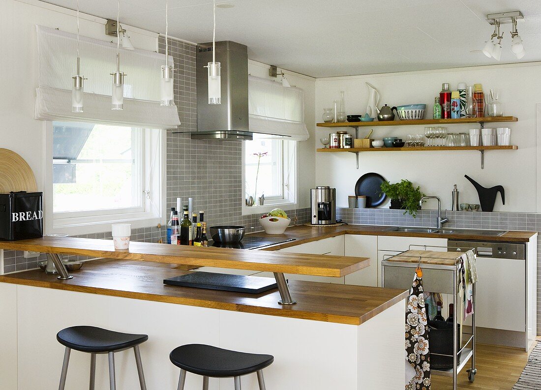 An open-plan kitchen - a counter and a shelf with a wooden work surface and white cupboards