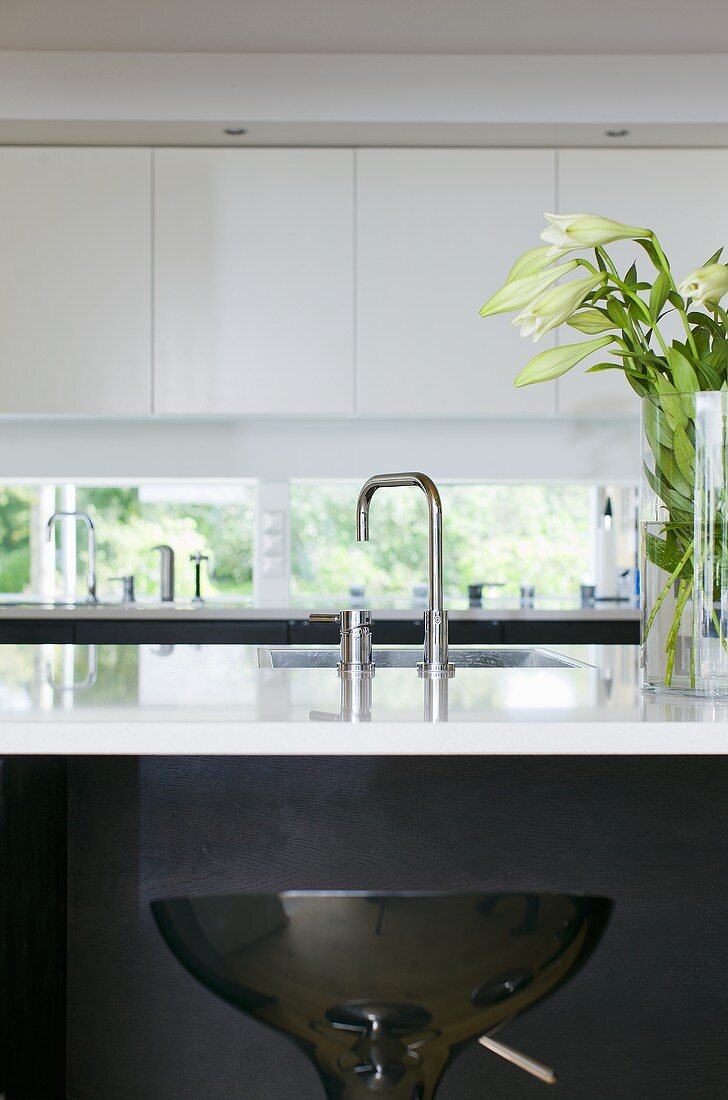 A kitchen counter - a sink with designer taps and a white shiny work surface