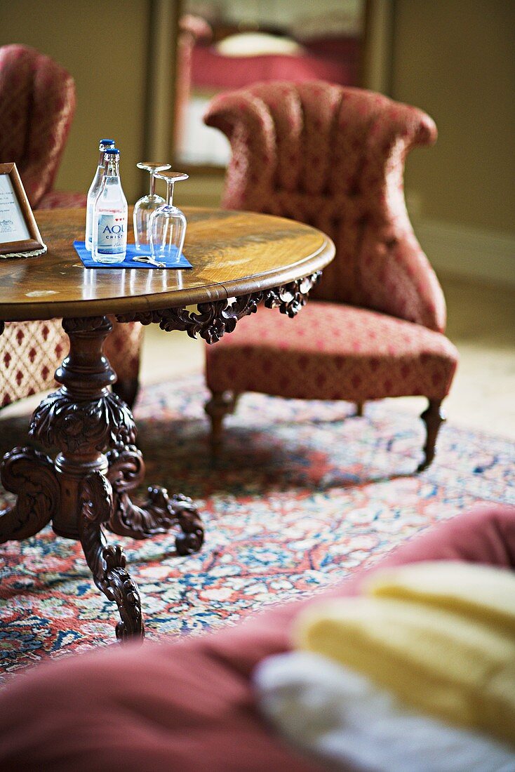 Getränke auf barockem Holztisch und gemusterte Sessel