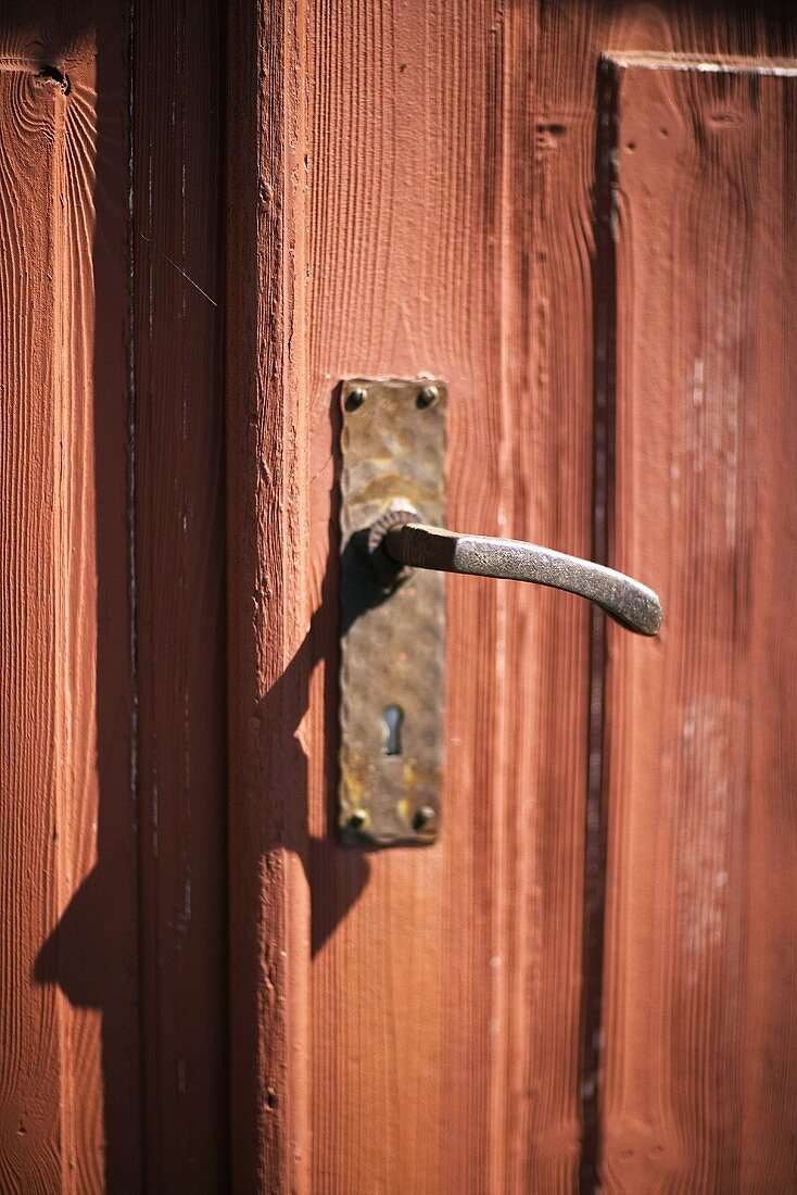 Alte Holztür rotgestrichen mit handgefertigtem Türgriff aus Metall