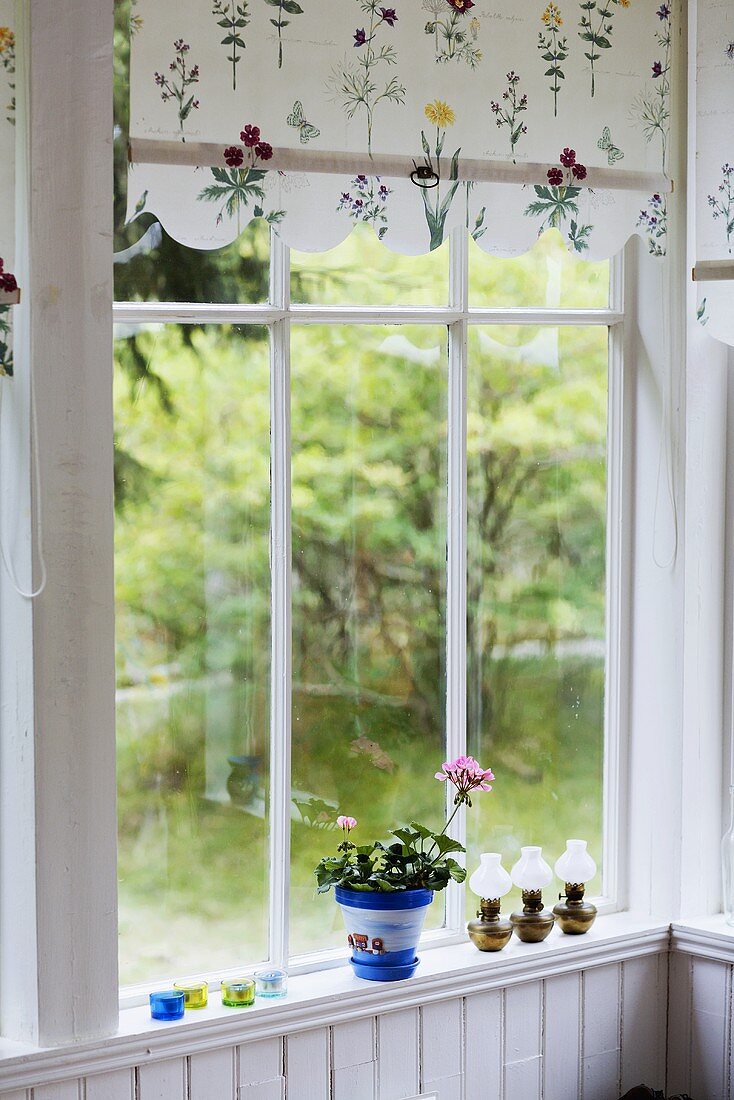 Fenster mit geblümter Vorhangblende und Blick in Garten