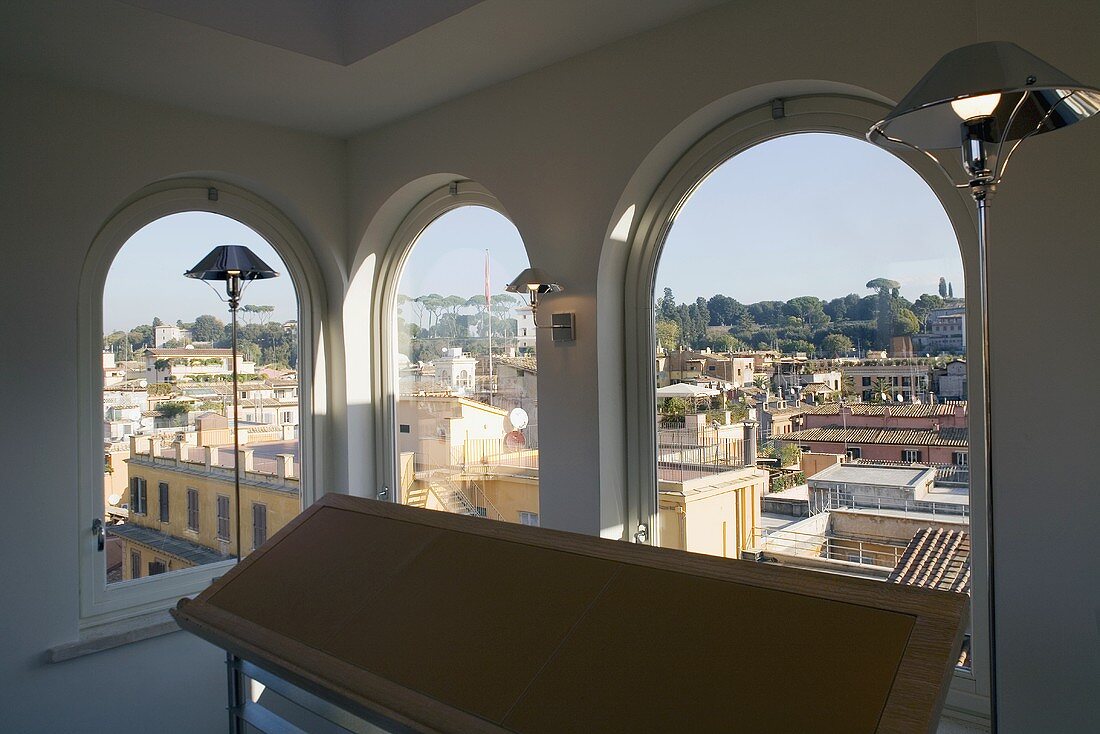 Floor lamps in a room with arched windows and a view of a Mediterranean city