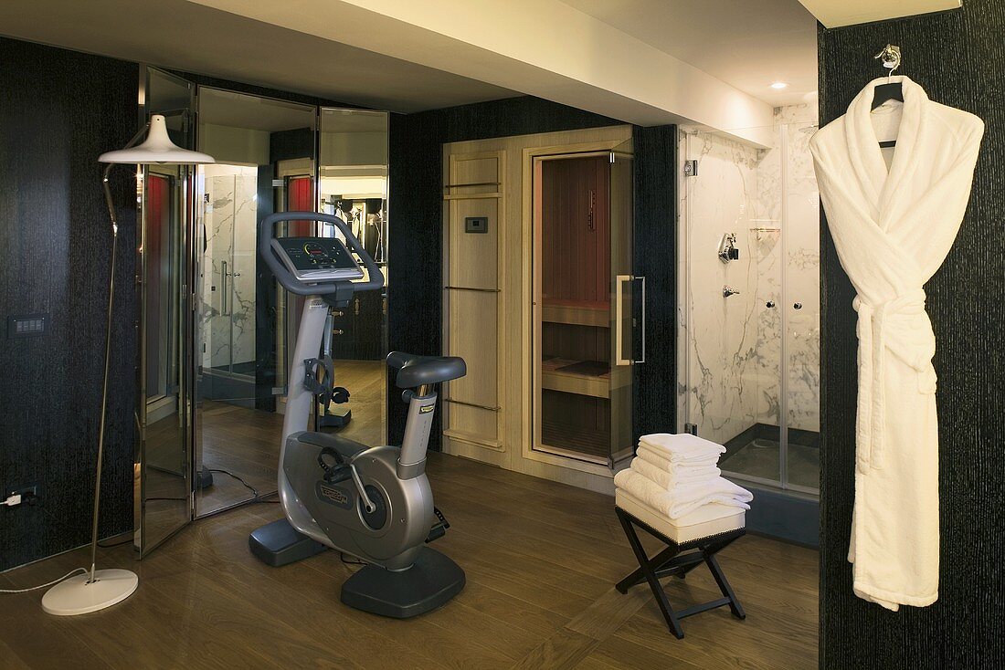 Gym equipment in front of mirrored closet doors and sauna with glass shower doors