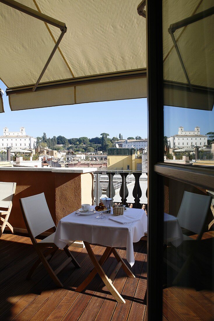 View of a roof terrace with set table under an awning and a view of a city