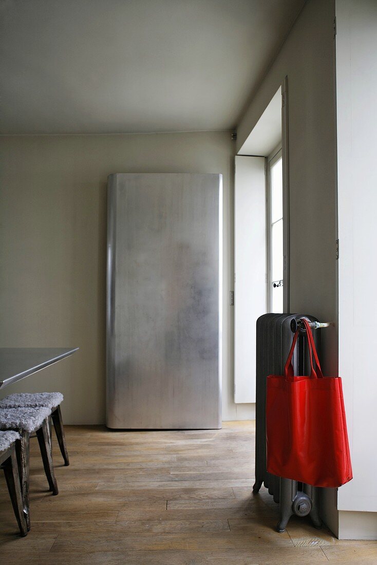 Simple closet and red bag hanging on a radiator in a minimalist dining area