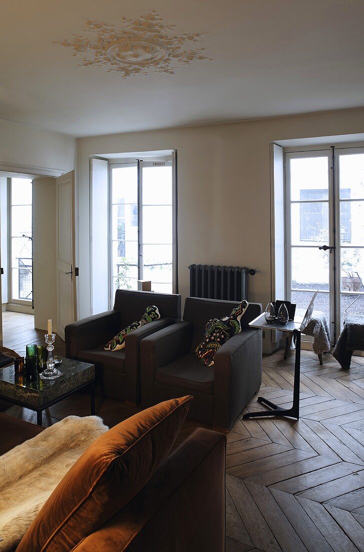 Schwarze Sessel im Wohnraum einer Villa mit raumhohen Fenstern
