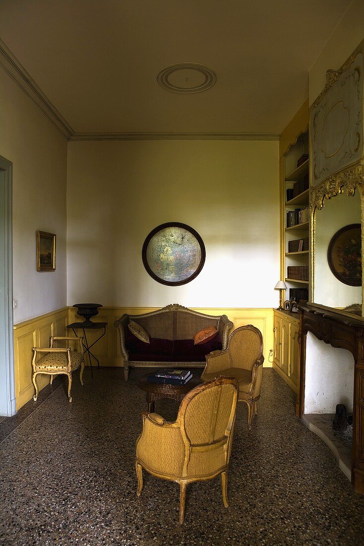 Half-darkened living room with the wood paneling and period furniture covered in yellow fabric