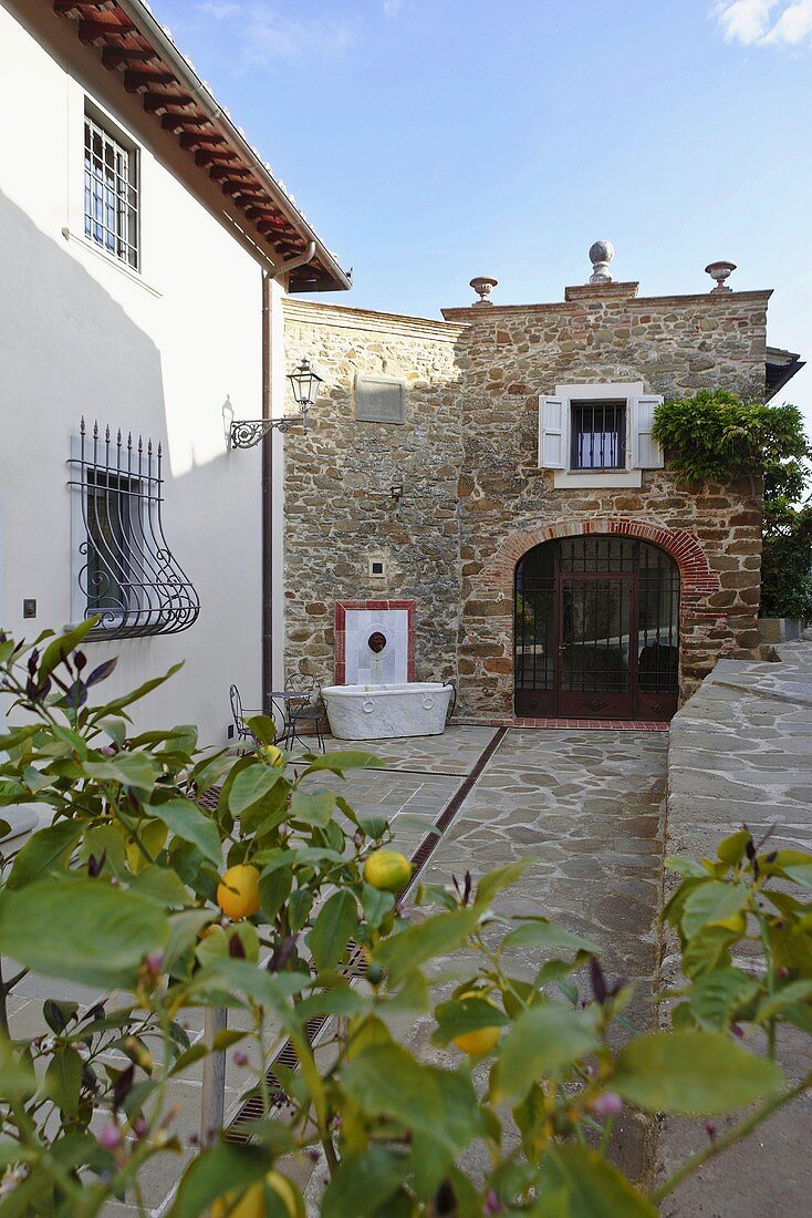 Courtyard of a Mediterranean country home with view of an old home made of natural stone