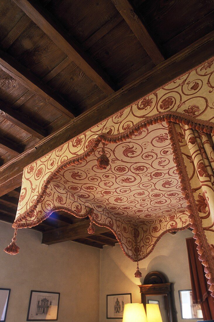 View of the canopy of a canopy bed under a rustic beam ceiling