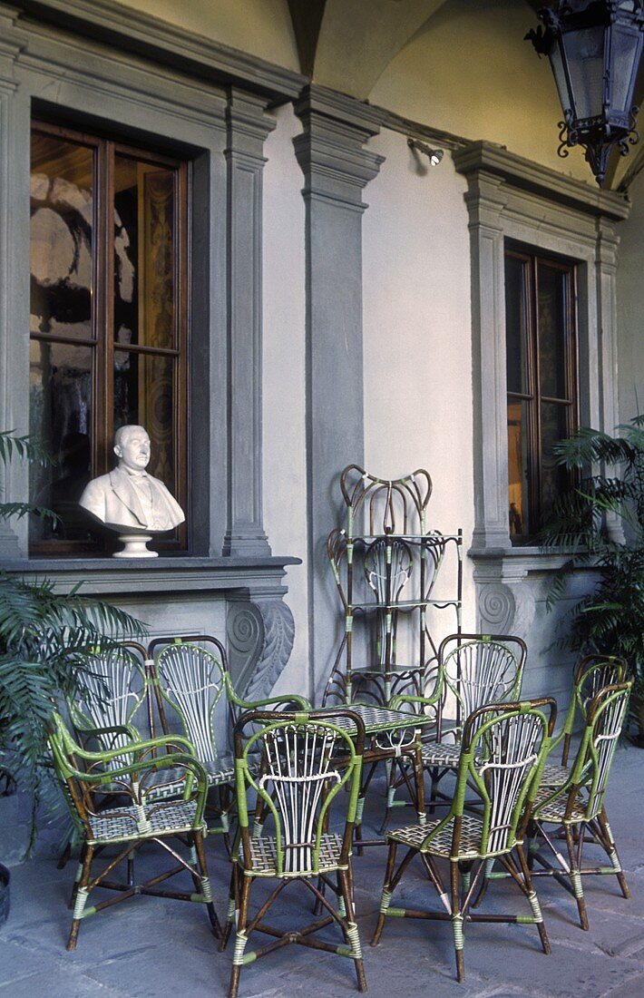 Terrace with rattan furniture and busts on a window ledge in a villa