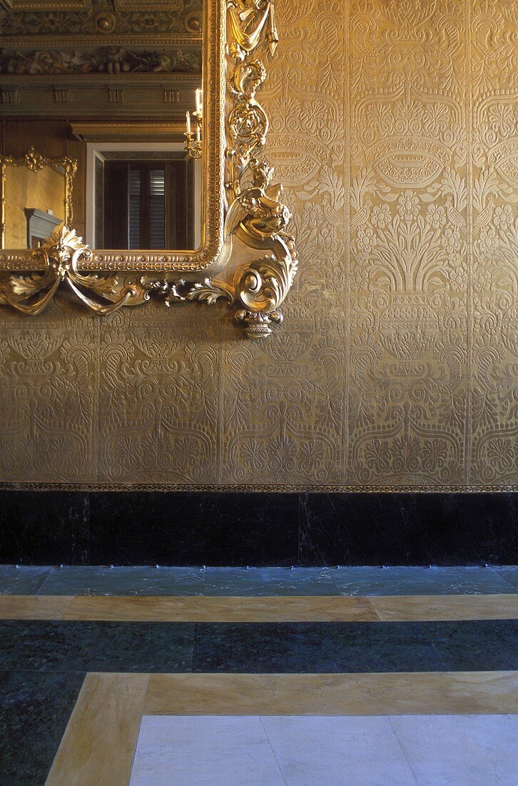 Mirror with a gold frame on a wall with gold wallpaper