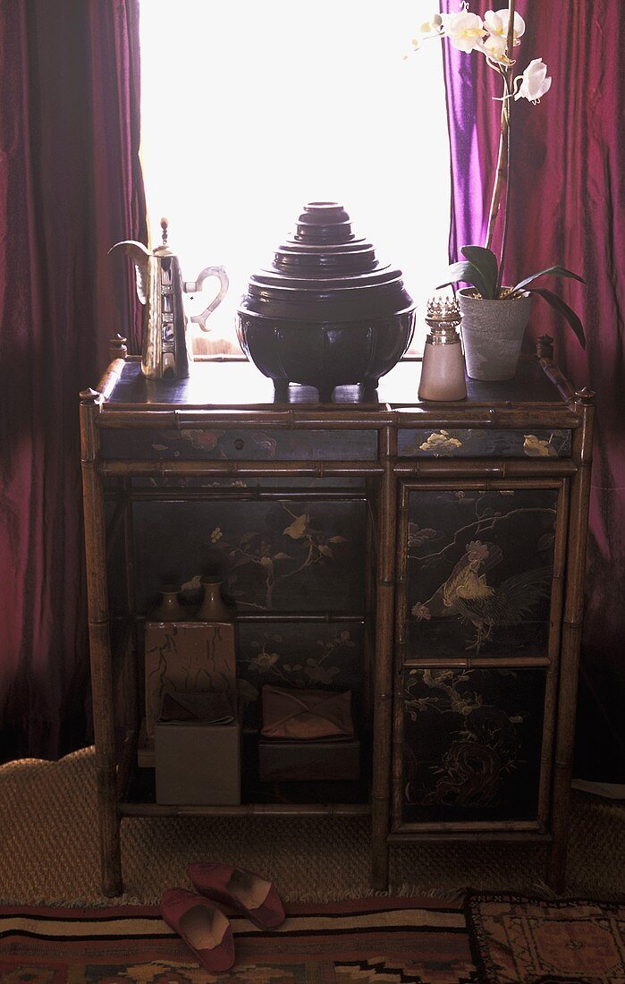 Rattan chest of drawers with a painted front in front of a window