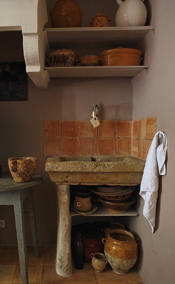 Rustikales Spülbecken aus Stein mit Terrakottawandfliesen und Schüsseln auf Ablage
