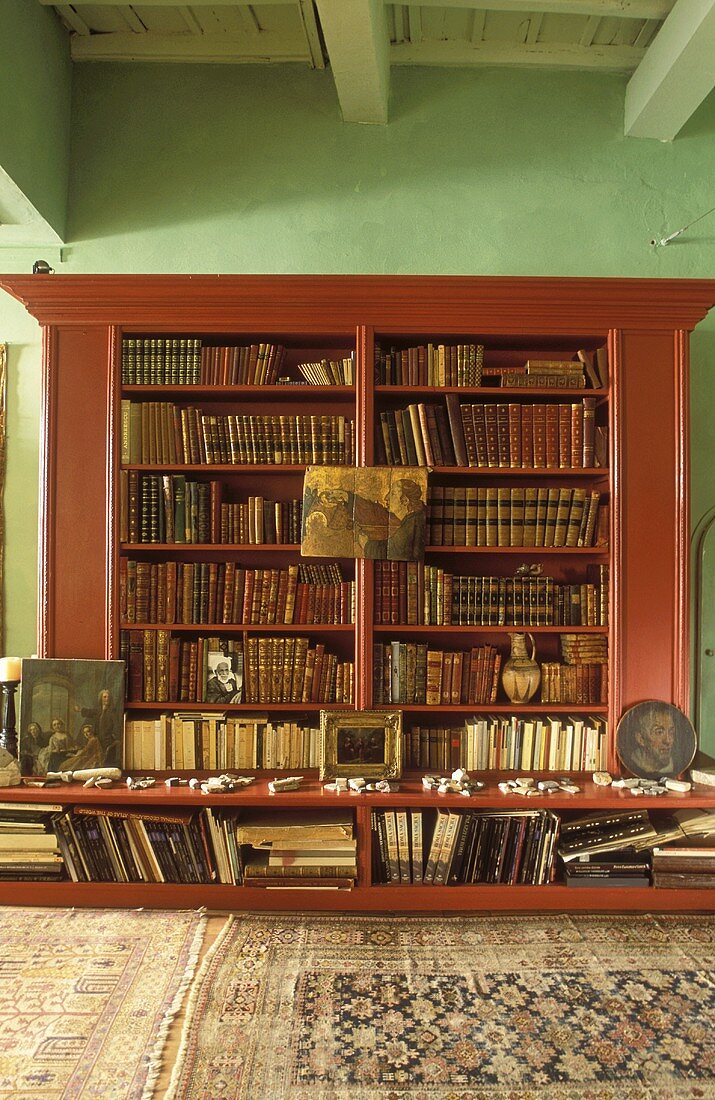 Mahogany bookcase against green wall