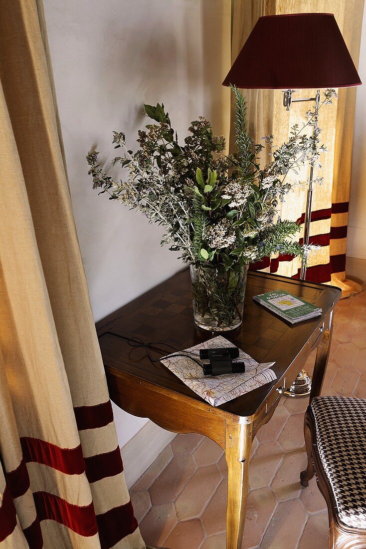 Wandtisch aus Holz mit Blumenvase und Stehlampe auf Terrakottaboden