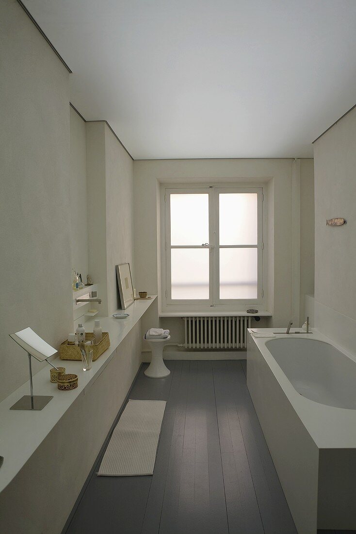 White designer style bathroom with a wide countertop in front of a wall with gray lacquer engineered flooring