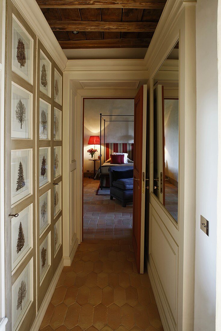 Narrow hallway with a picture gallery and open door with a view of a canopy bed