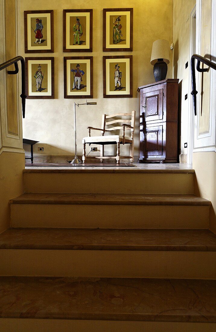 Treppenaufgang mit Blick auf Bildersammlung und Stuhl neben Eckschrank