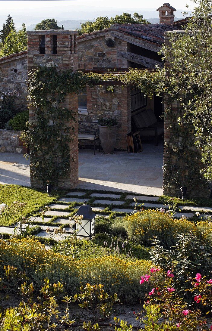 View across the professionally designed garden of a Mediterranean villa with a natural stone facade