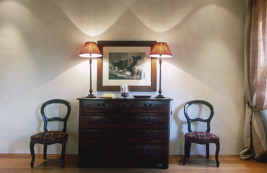 Dramatic wall lighting from two table lamps on an antique chest of drawers