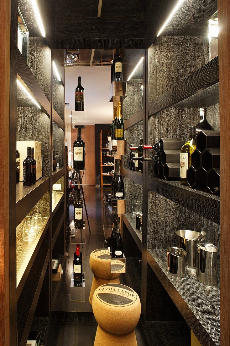Wine store with black wooden shelves and wine bottles on display and stools shaped like corks
