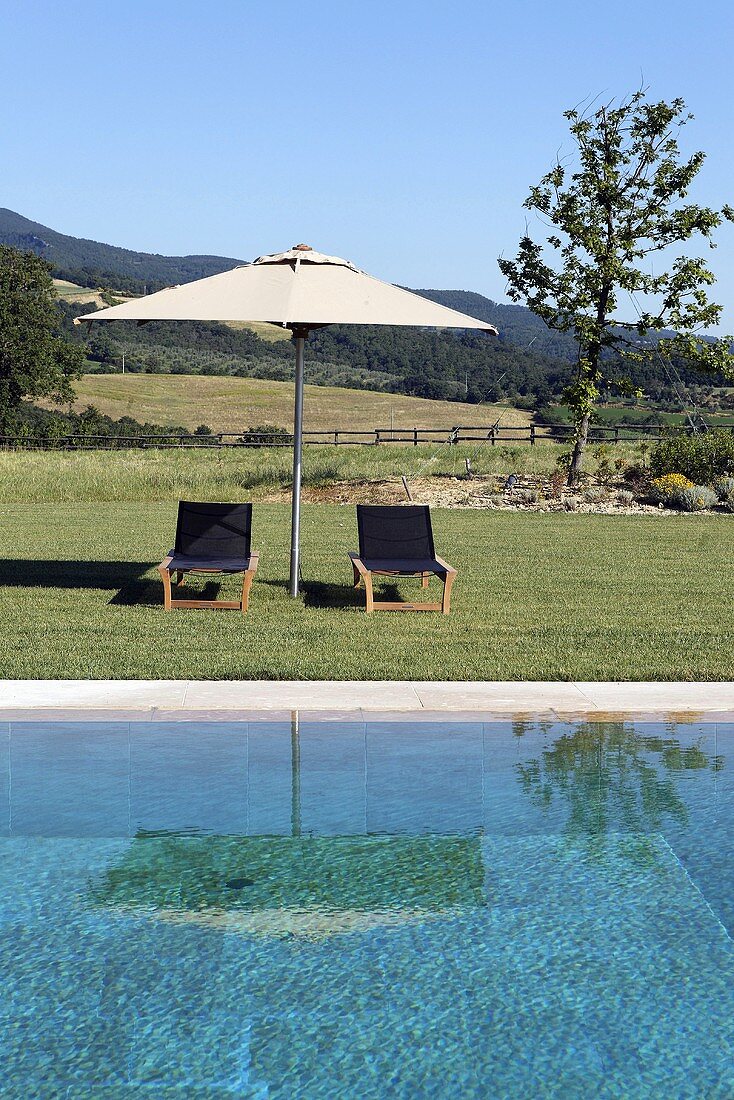 Entspannung am Pool mit Liegestühlen unter Sonnenschirm, und Blick auf Mediterraner Landschaft