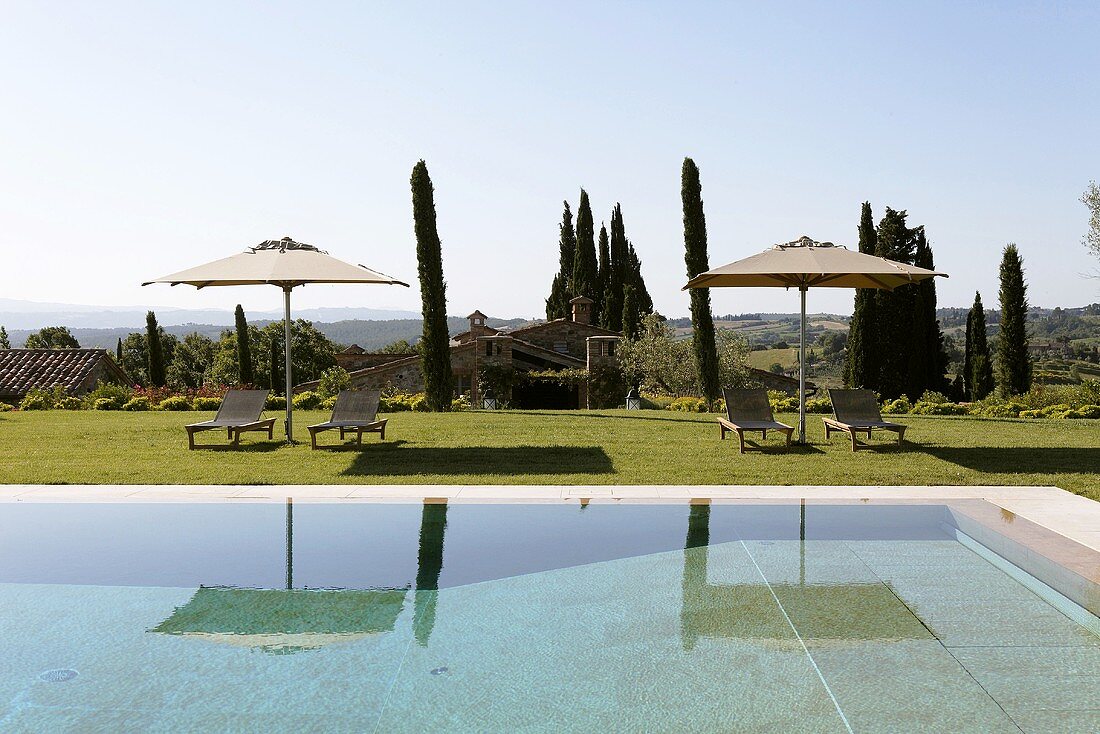 Relaxing hours, poolside, with lounge chairs under a sun umbrella and a view of the Mediterranean countryside