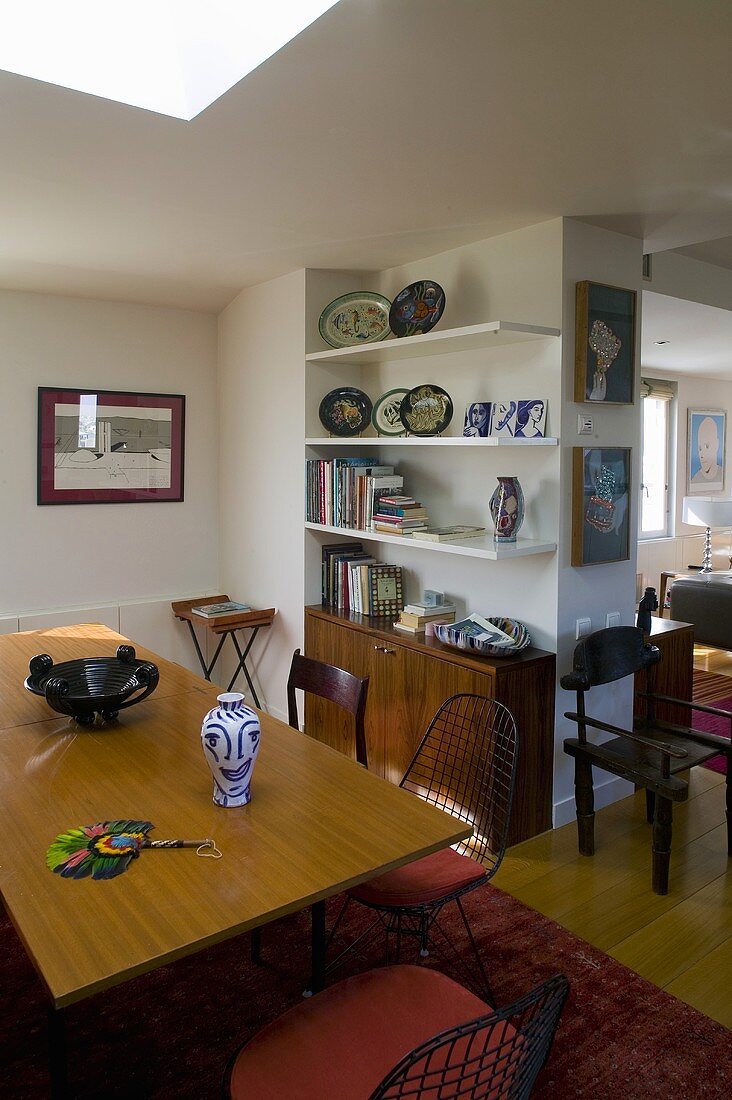Open dining room -- table in front of wall shelving with wooden cupboards