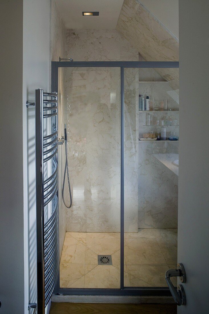 Built in shower under a roof with glass doors and a stainless steel heated towel rail