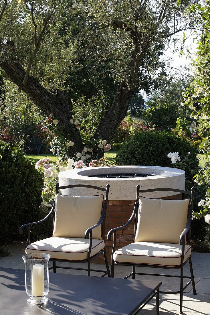 Elegant patio chairs upholstered in bright fabric in front of a circular grill